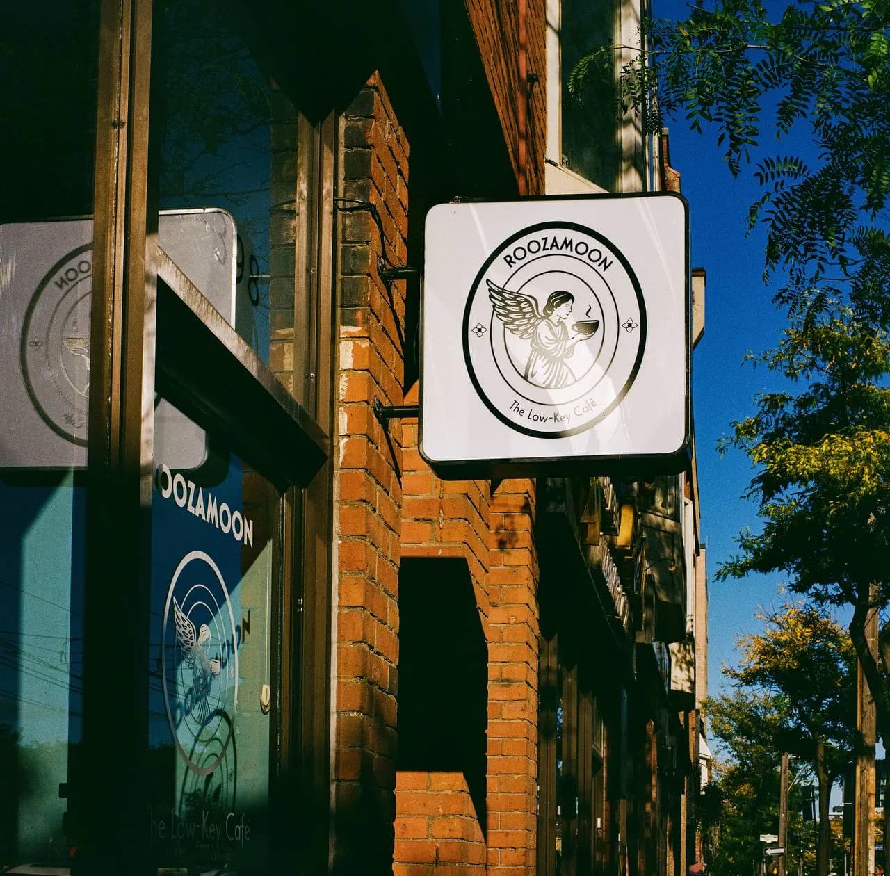 The Roozamoon sign hanging from the brick wall against a blue sky