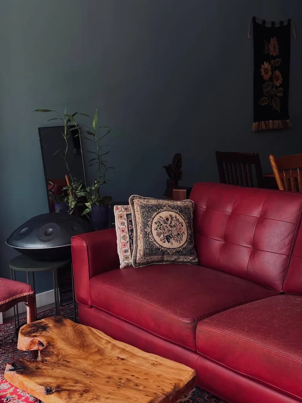The red leather sofa with an embroidered cushion and a wooden slab table
