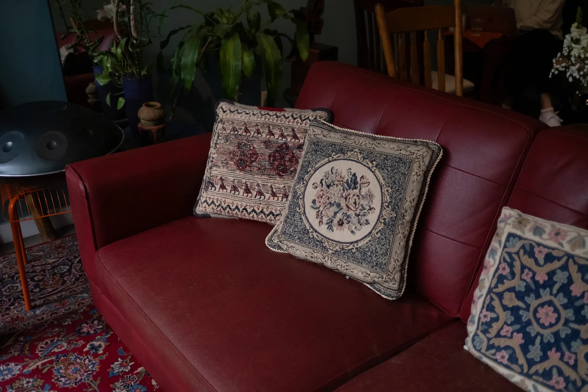 Three embroidered cushions on the red leather sofa