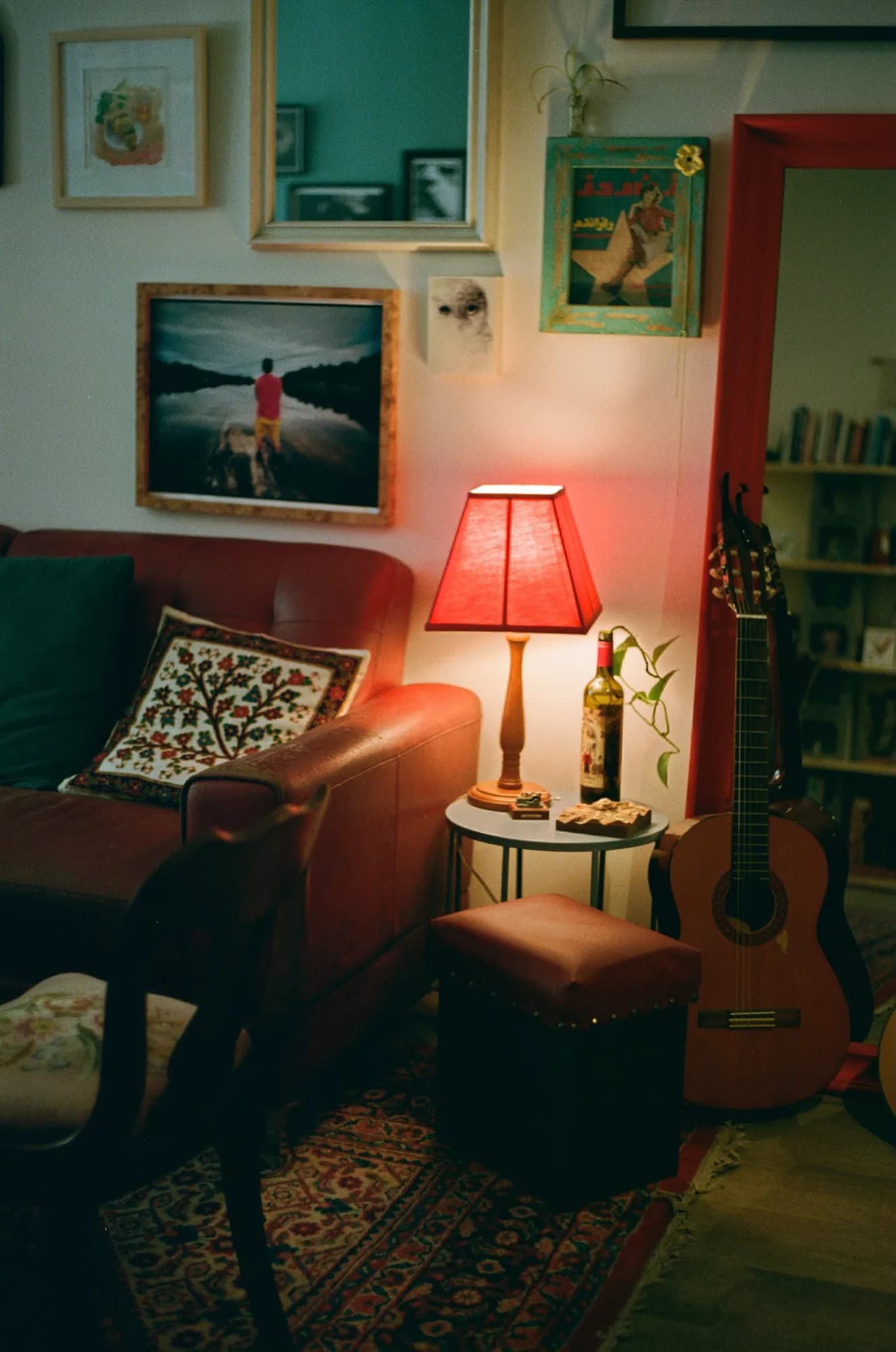 A reading nook lit by a red lamp, with a guitar and framed pictures