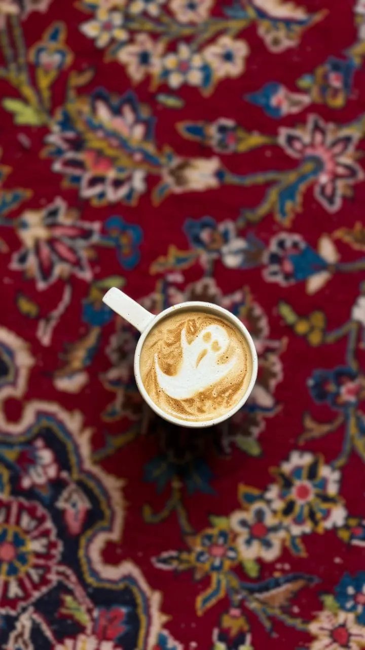 A latte with latte art, seen from above on a Persian rug