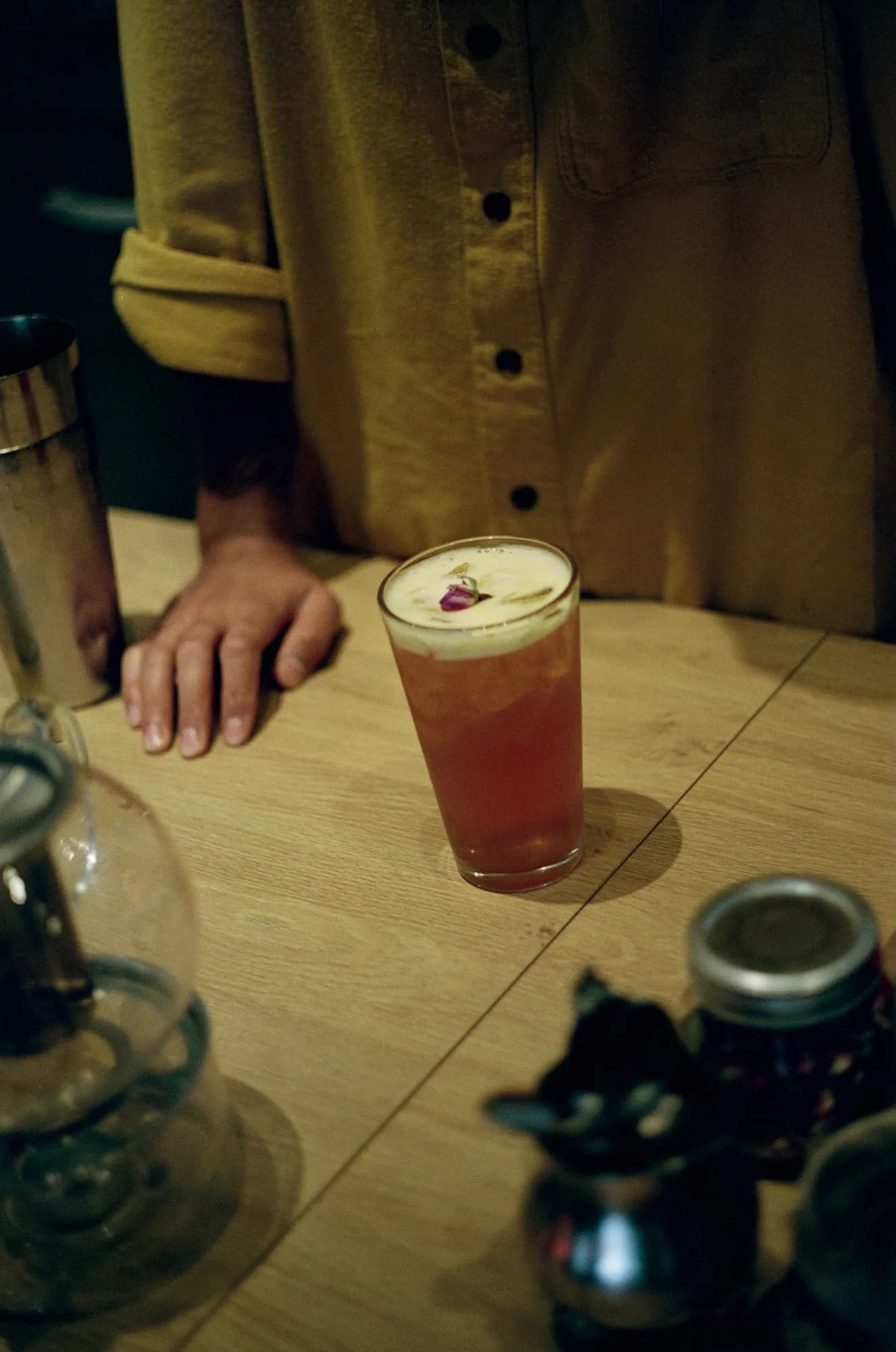 A pink iced drink topped with a flower on a wooden table