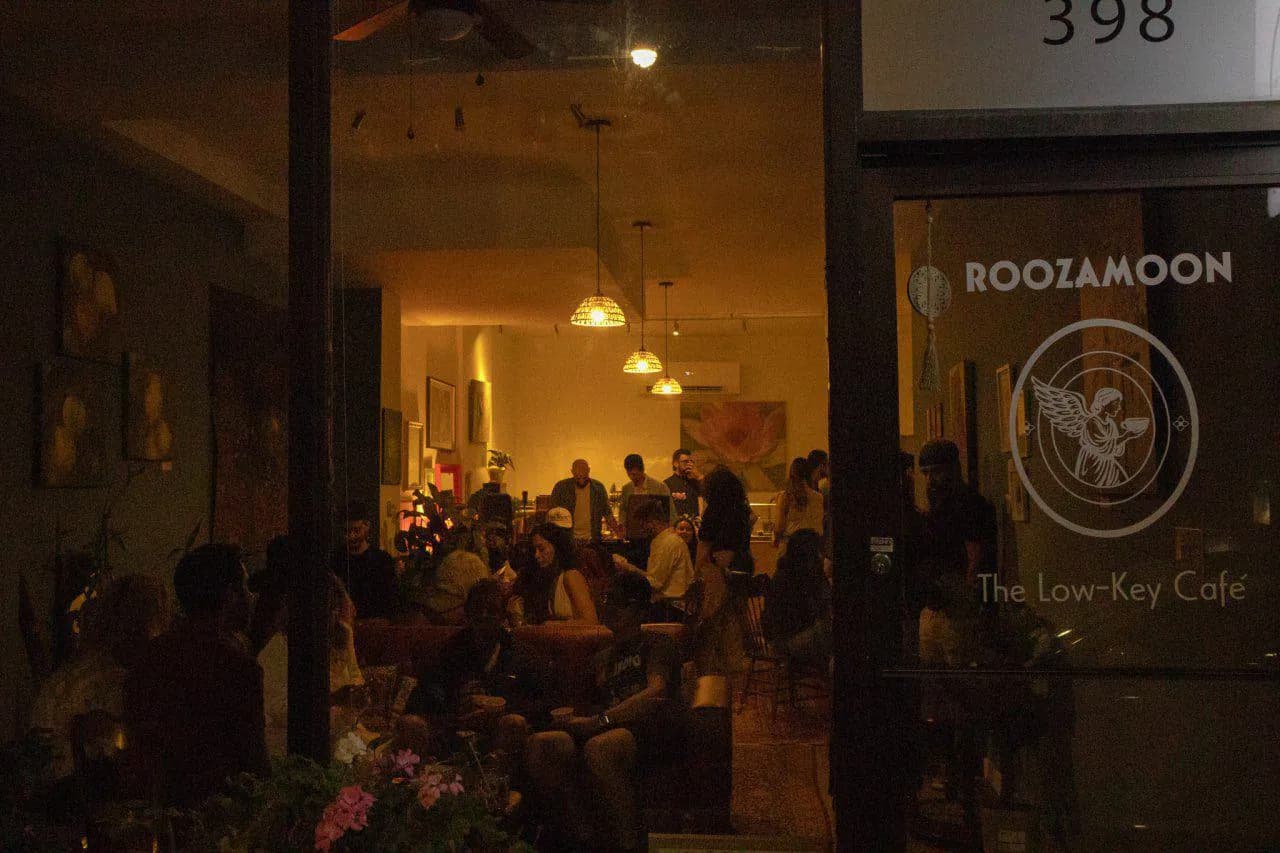 Roozamoon at night from the street: a full room under warm pendant lights
